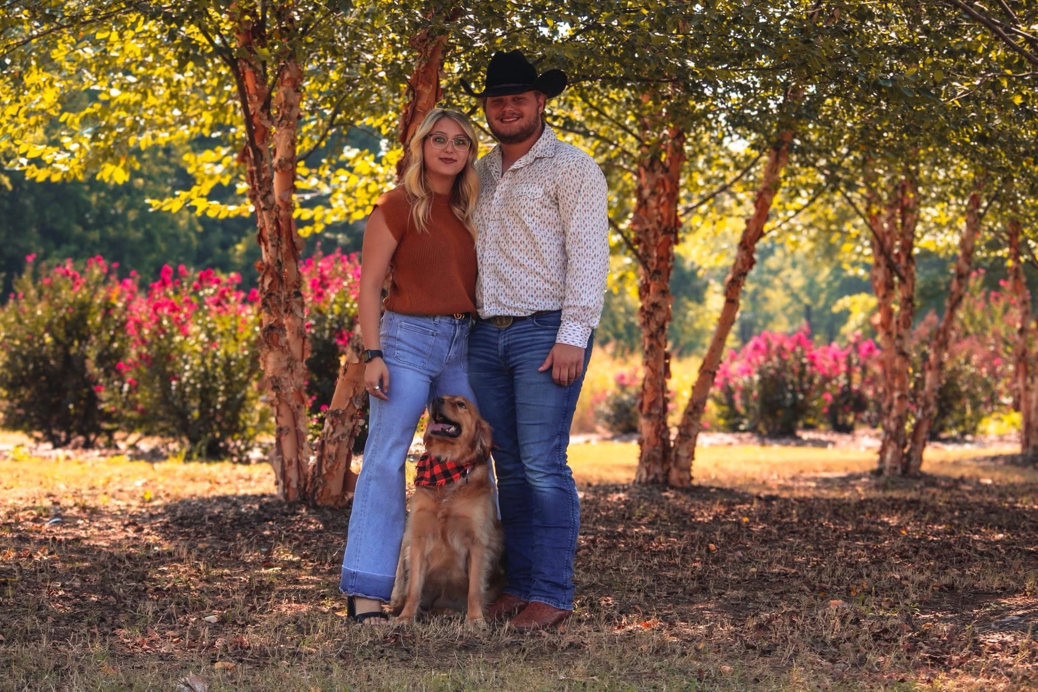 Couple and their golden retriever under flowering trees