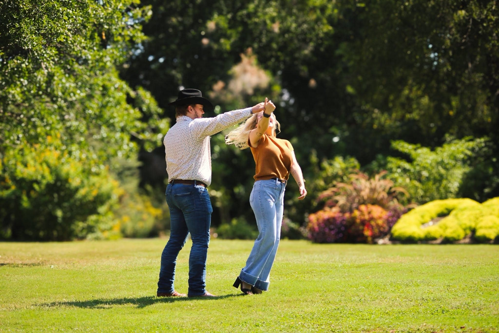 Cowboy twirling his partner on a green lawn