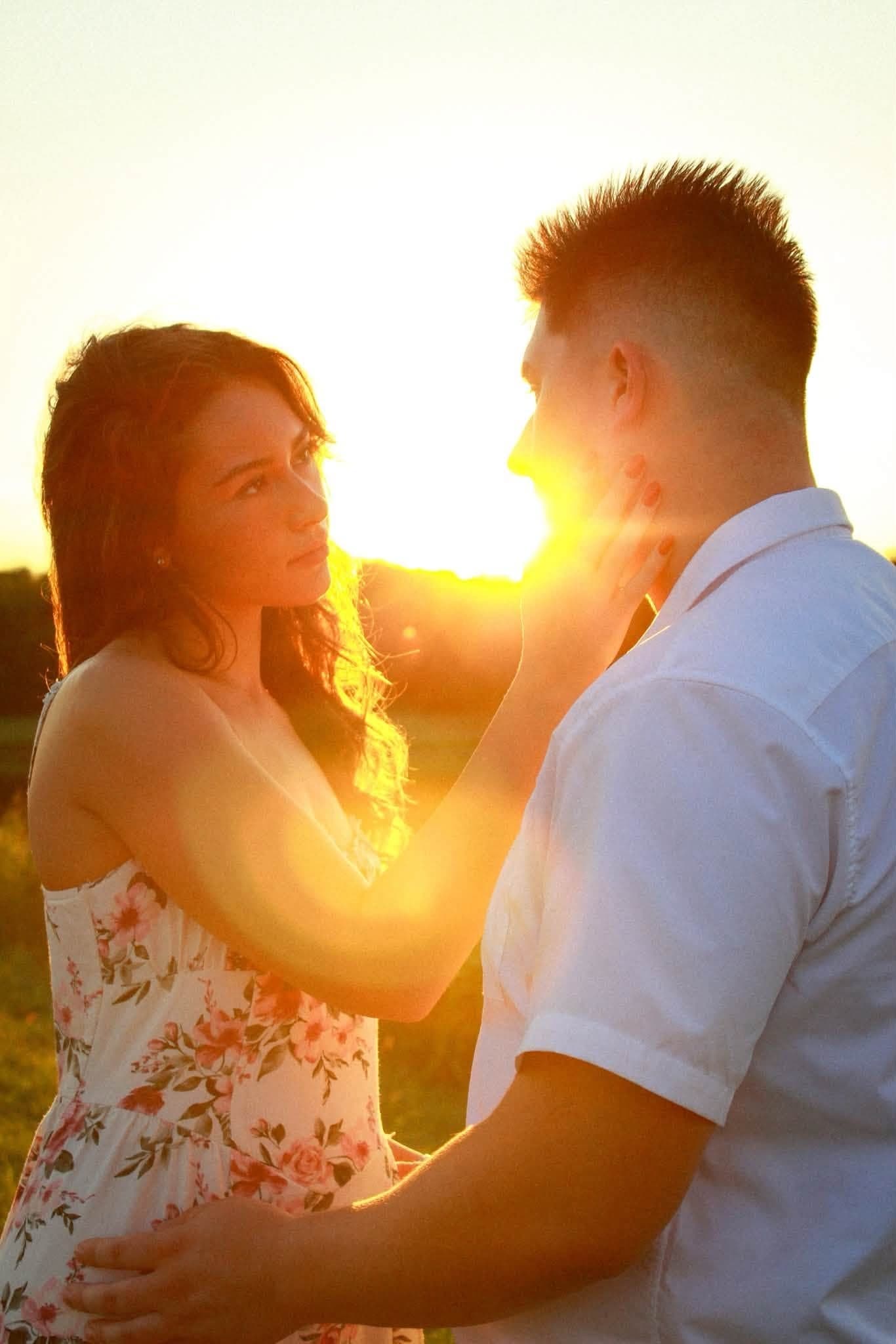 Couple face to face with the setting sun flaring between them